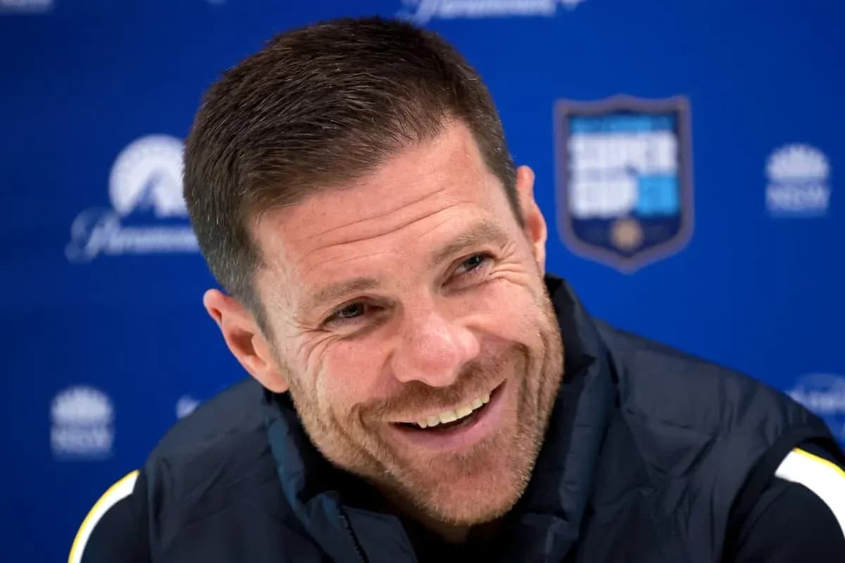 Coach smiling during press conference with backdrop