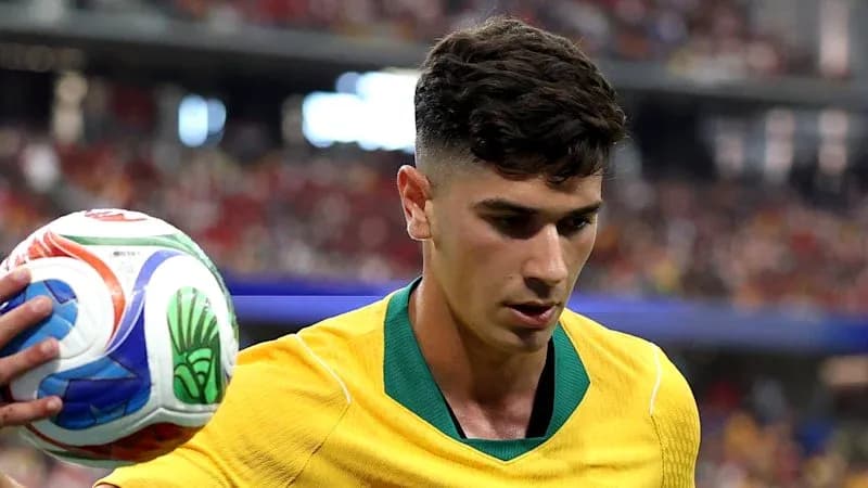 Player in yellow kit holding soccer ball during match