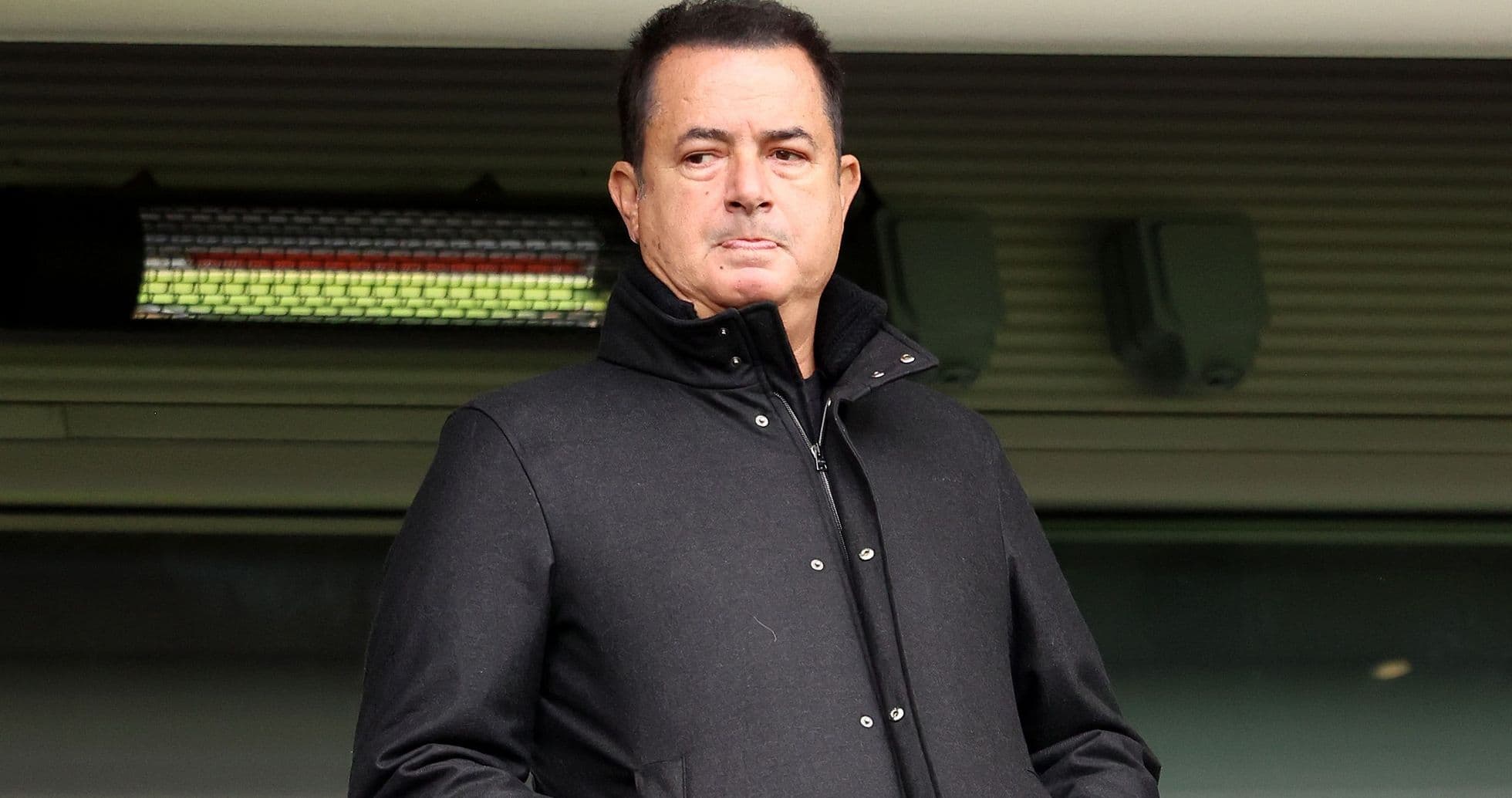 Man in black coat standing in stadium area