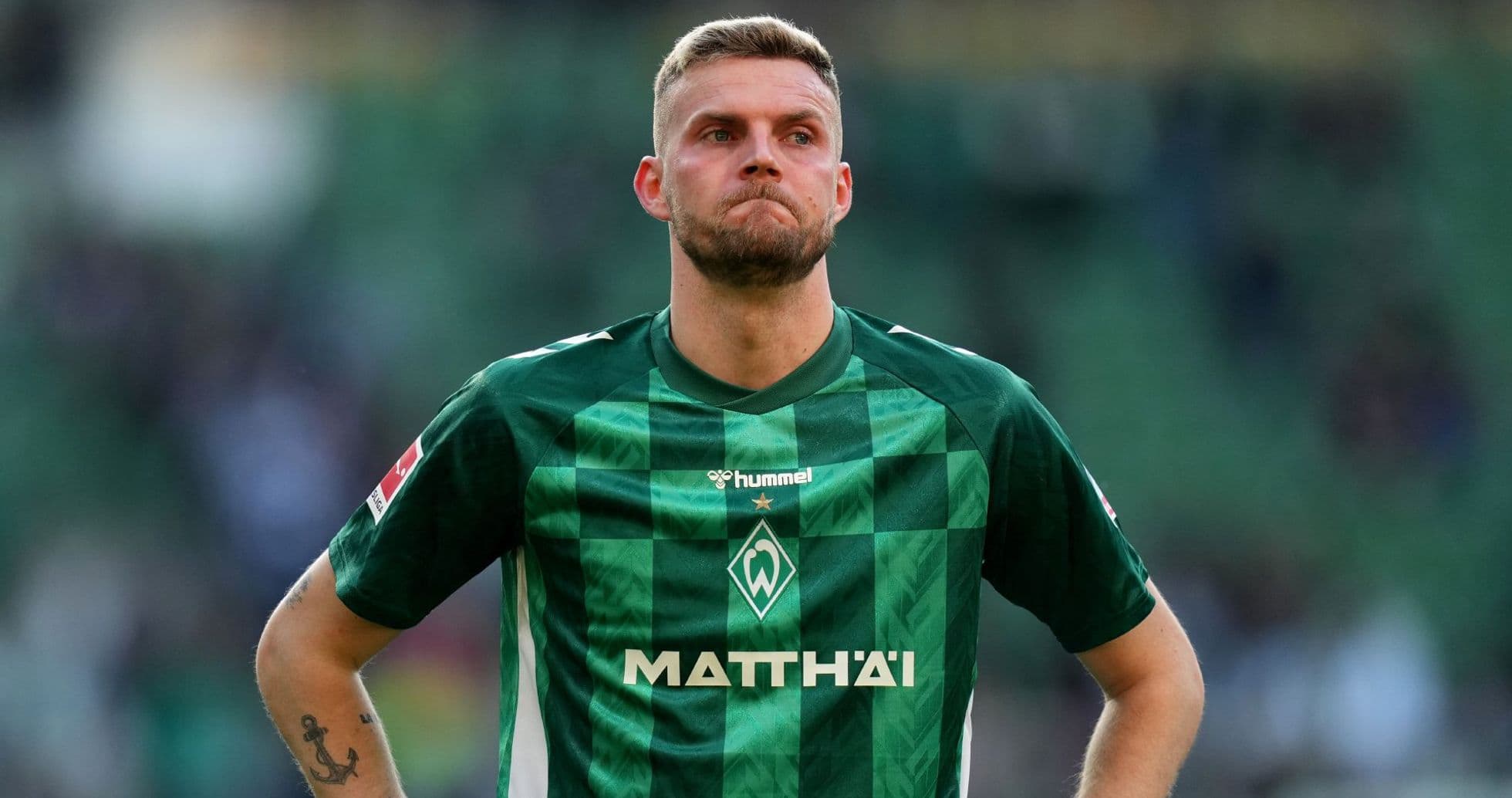 Player in green jersey looking down on field