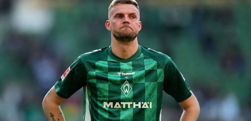 Player in green jersey looking down on field