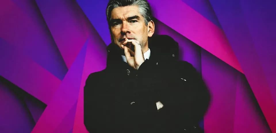 Man in black coat posing against colorful background