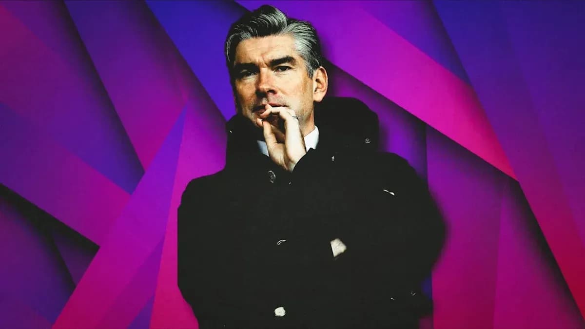 Man in black coat posing against colorful background