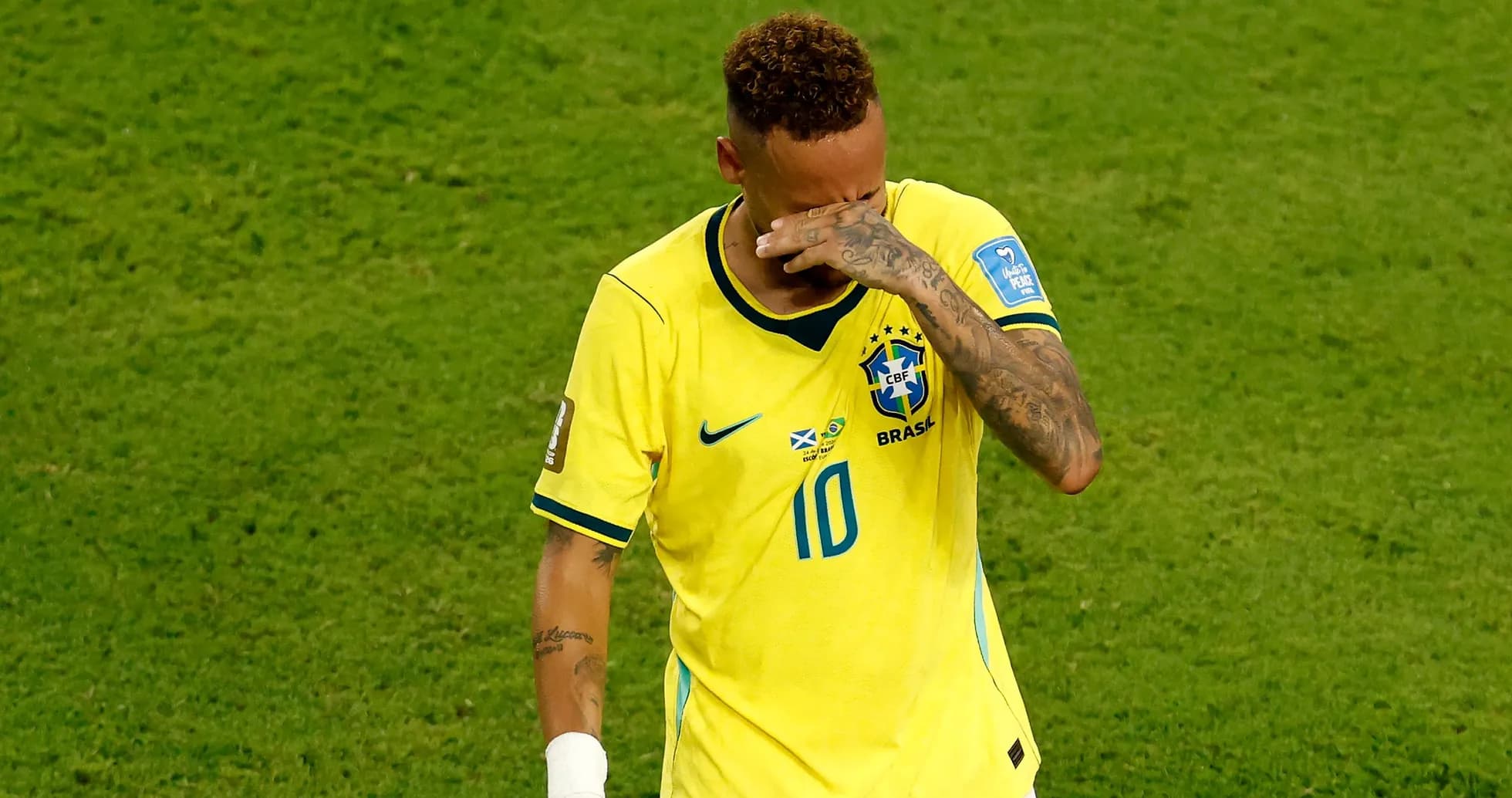 Player in yellow jersey wiping forehead on field