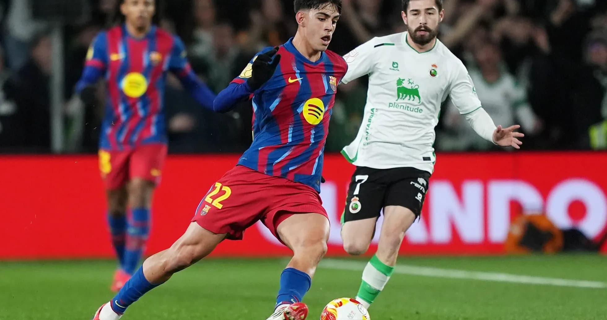 Barcelona player dribbling past Racing Santander defender