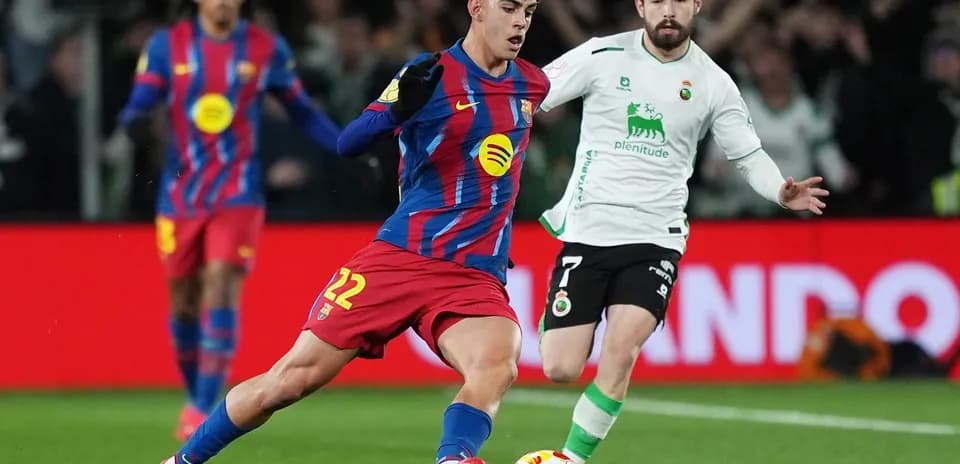 Barcelona player dribbling past Racing Santander defender