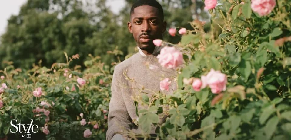 Man seated among blooming pink roses in garden