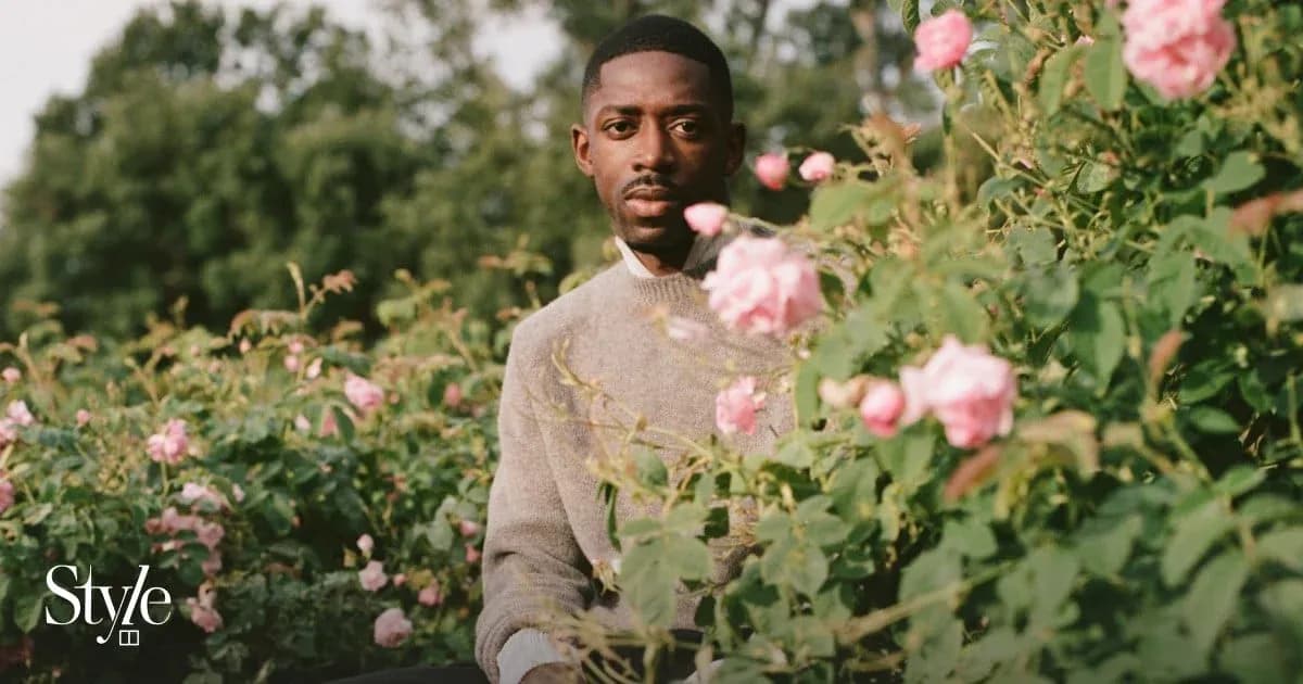 Man seated among blooming pink roses in garden