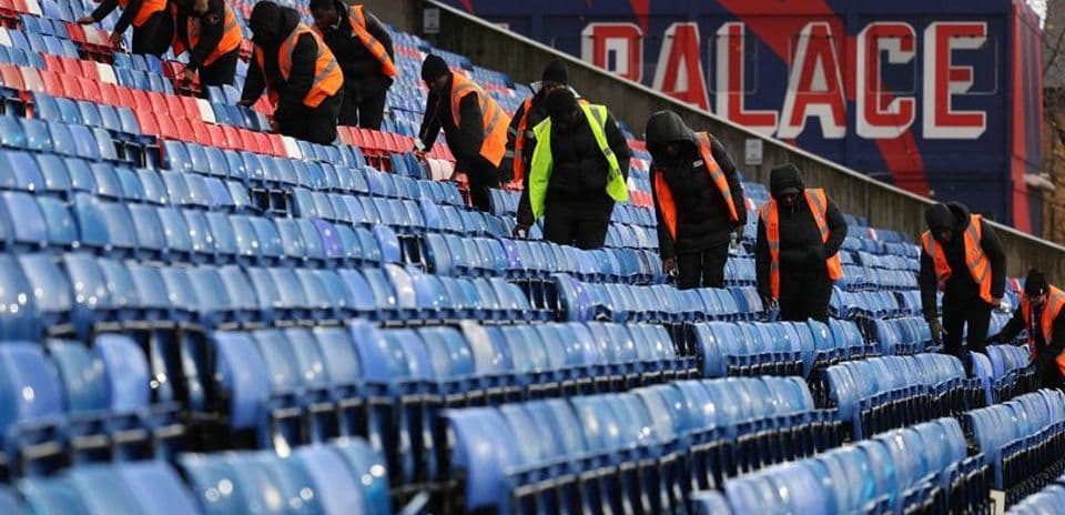 Staff cleaning seats in stadium stands before event