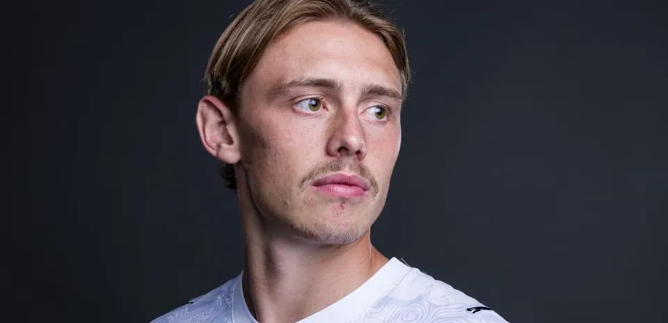 Player in white jersey posing against dark background