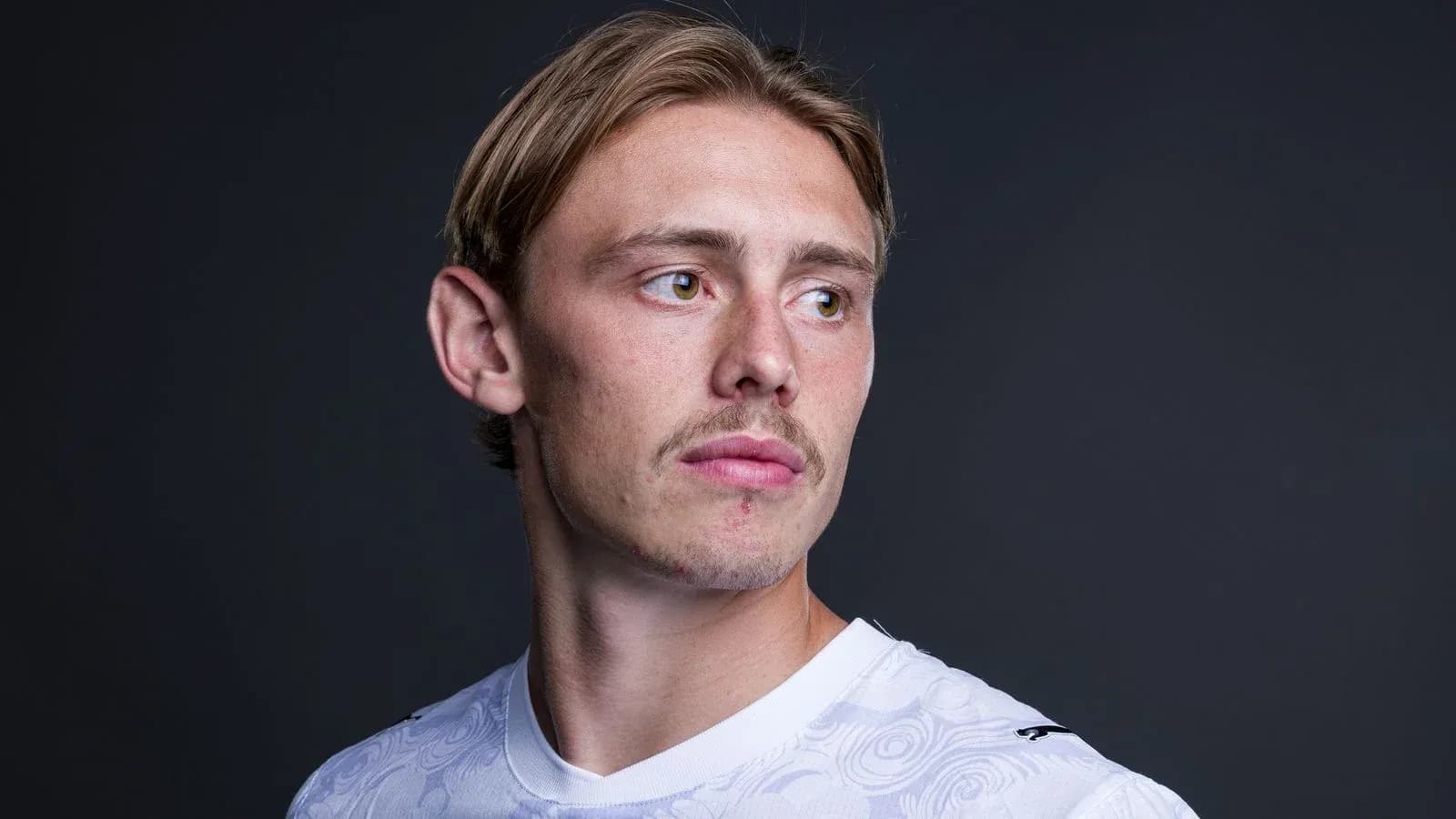 Player in white jersey posing against dark background
