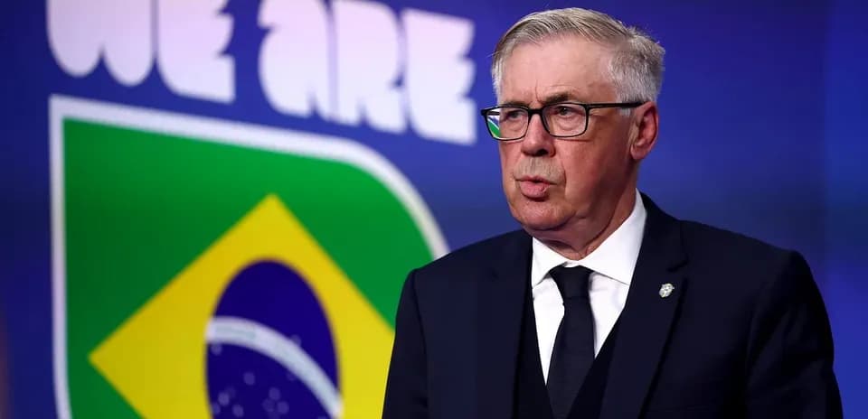 Coach speaking at press conference with Brazil logo behind