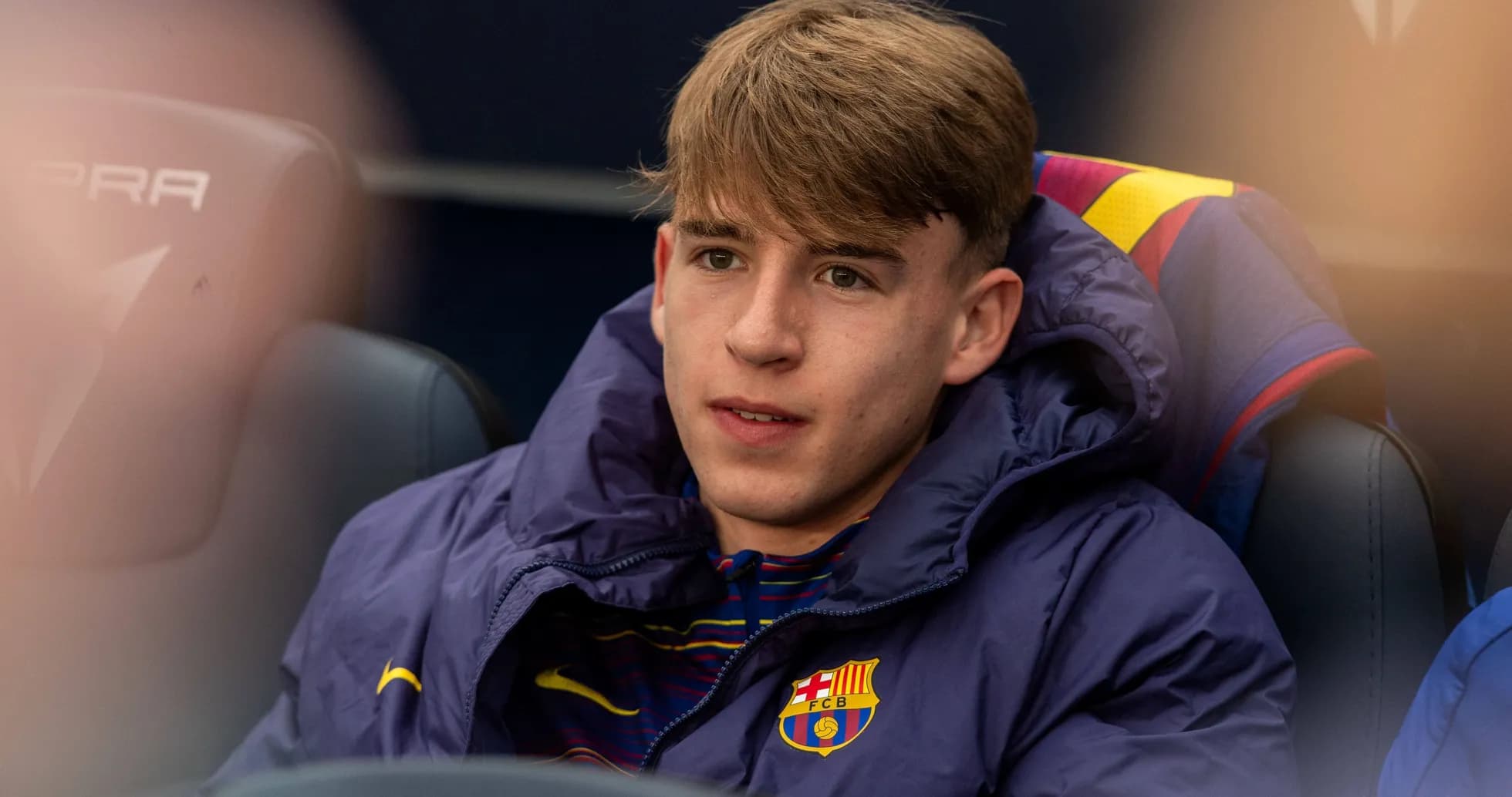Young player sitting on bench in team jacket