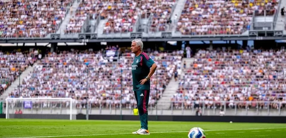 Coach observing match from sideline with crowd in background