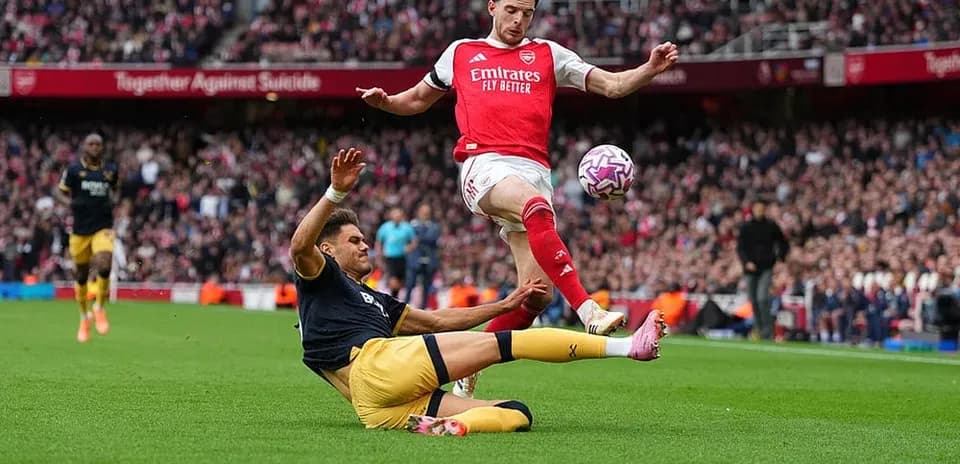 Arsenal player dodging a tackle during match