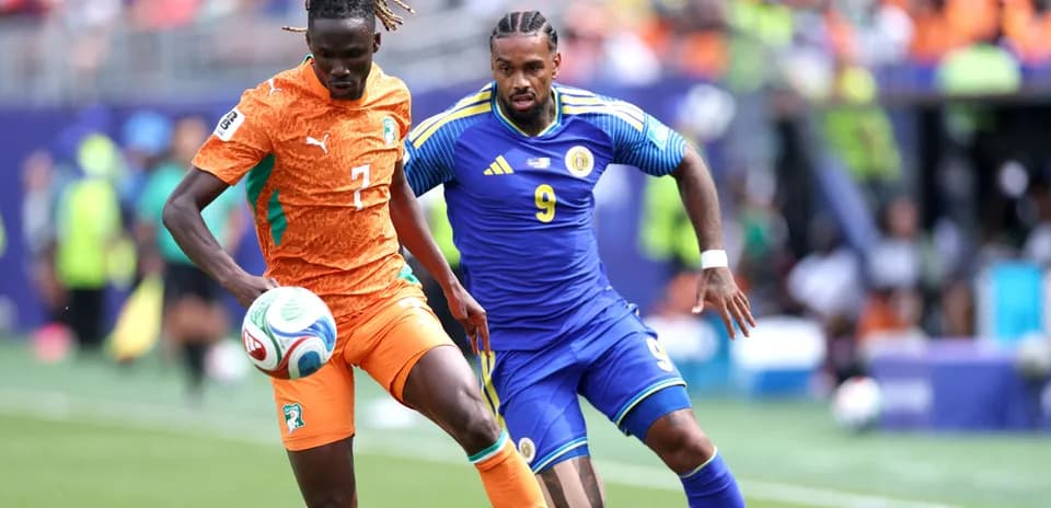 Player in orange dribbling past opponent in blue