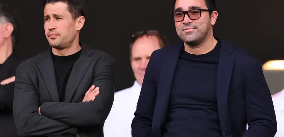 Two men seated in a sports venue watching event