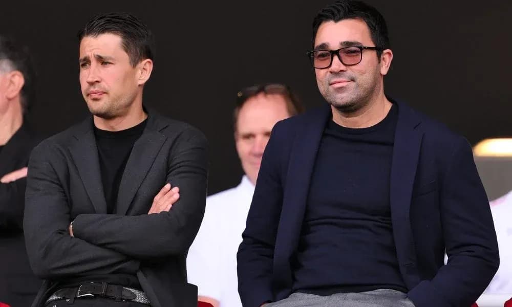 Two men seated in a sports venue watching event