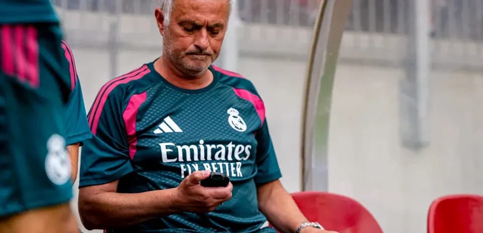 Coach sitting on bench looking at phone