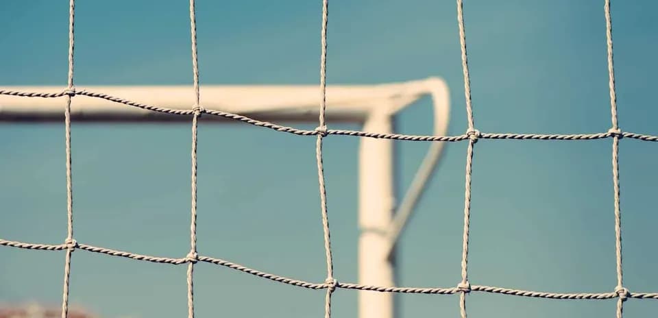 Close-up of soccer goal net against blue sky