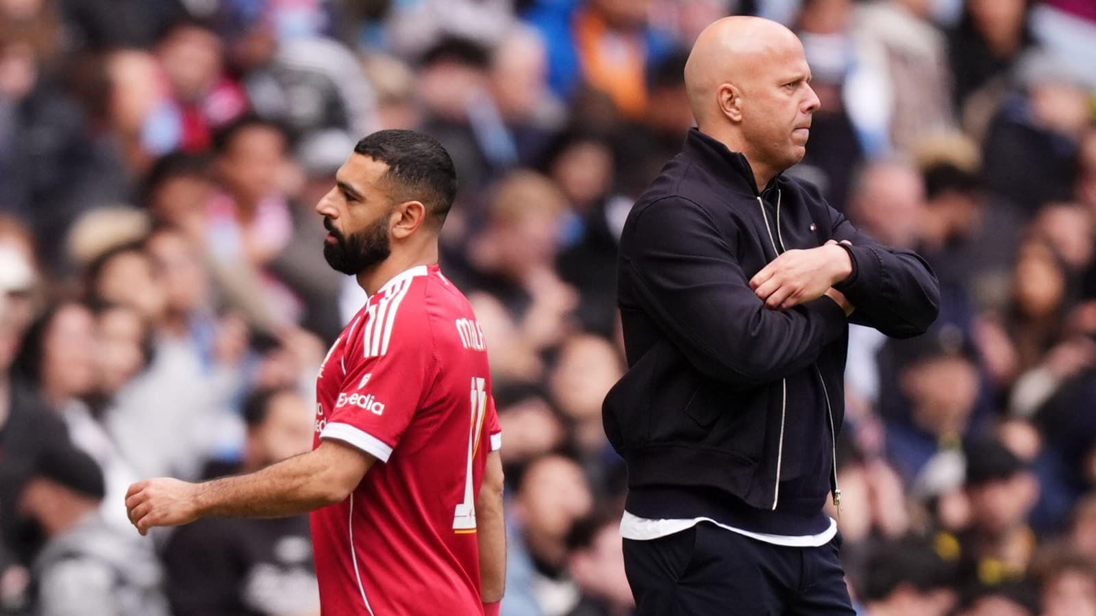 Player in red jersey walking past coach on sidelines