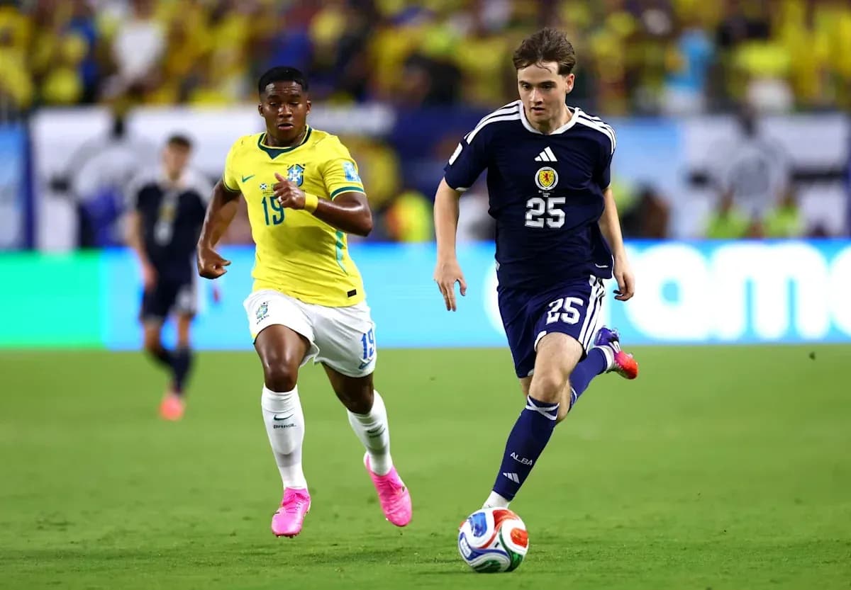 Player from Scotland dribbling ball, Brazilian player chasing