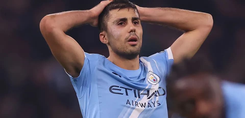 Player in Manchester City jersey holding head in frustration