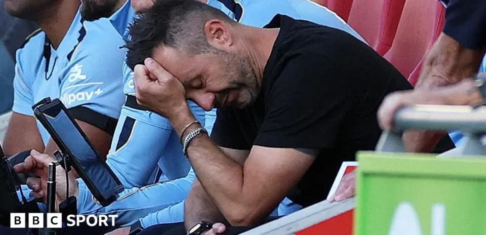 Coach sitting on bench with head in hand