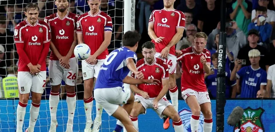 Player taking free kick while wall defends goal
