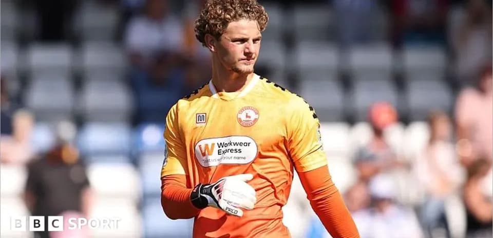 Goalkeeper in orange kit during match warm-up