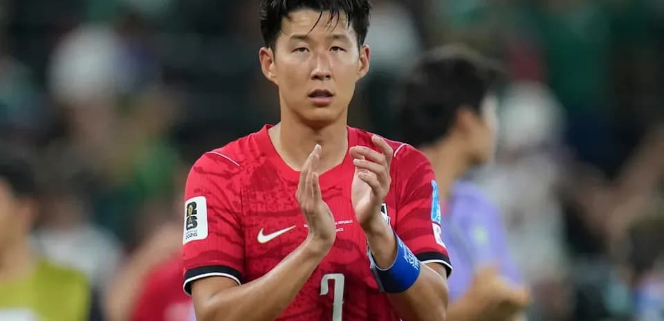 Player in red jersey applauding fans after match