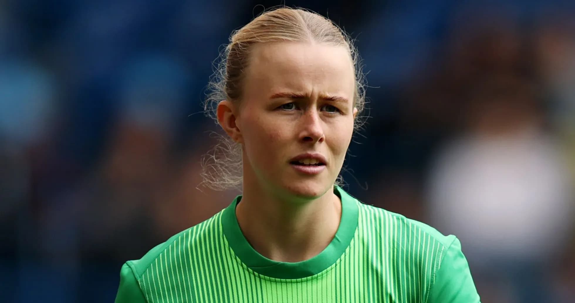 Female goalkeeper wearing green kit during match