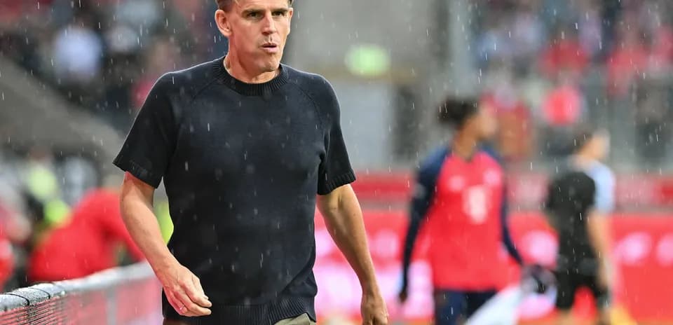 Coach walking along sideline in rainy match