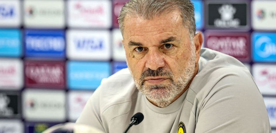 Manager at press conference with team logo visible