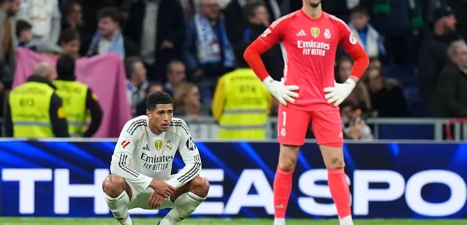 Real Madrid players seated and standing on the pitch
