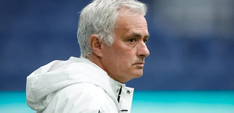 Coach observing match from sidelines in white jacket