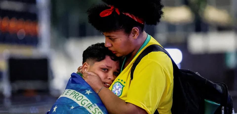 Mother comforting child wrapped in Brazilian flag