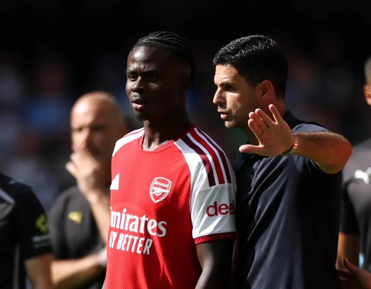 Arsenal coach discussing strategy with player on pitch Arsenal coach discussing strategy with player on pitch