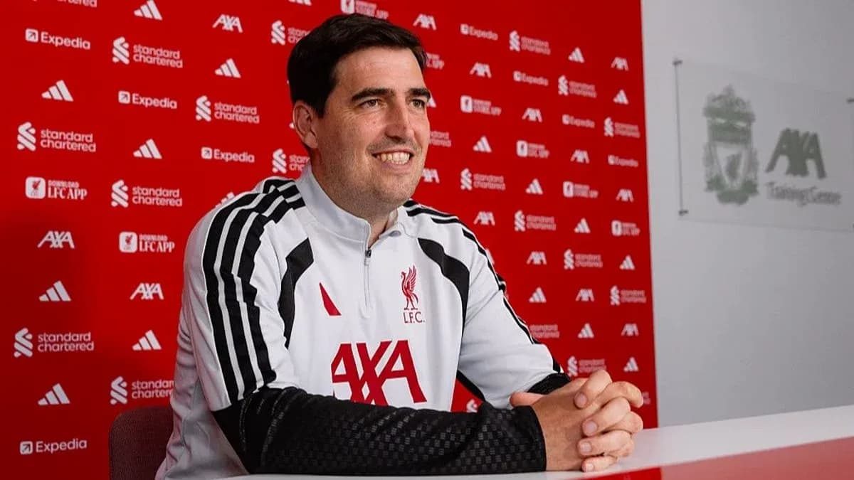 Manager seated at press conference table with Liverpool backdrop Manager seated at press conference table with Liverpool backdrop