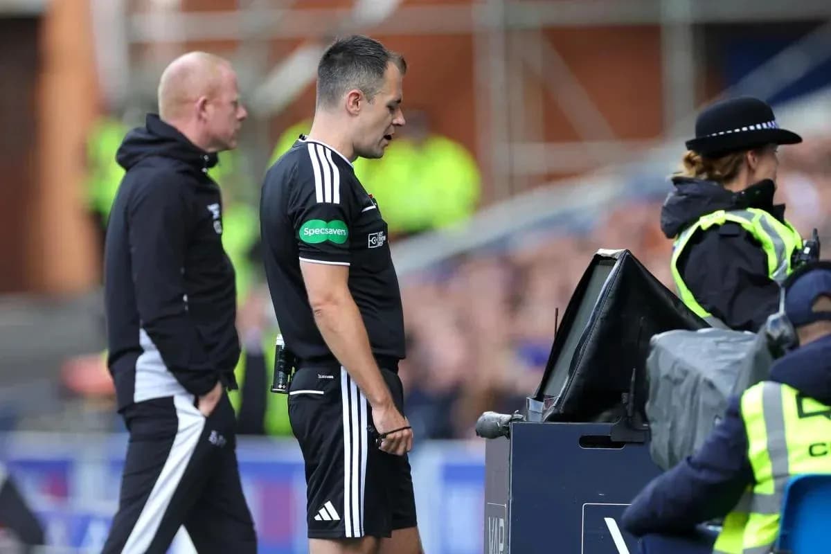 Referee reviewing VAR decision with assistant nearby Referee reviewing VAR decision with assistant nearby