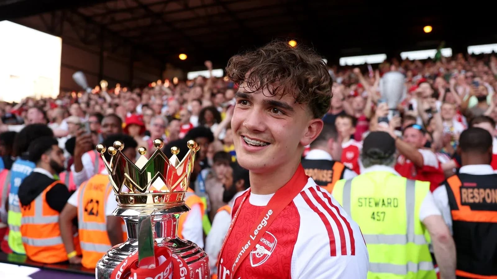 Player holding Premier League trophy with celebrating fans Player holding Premier League trophy with celebrating fans