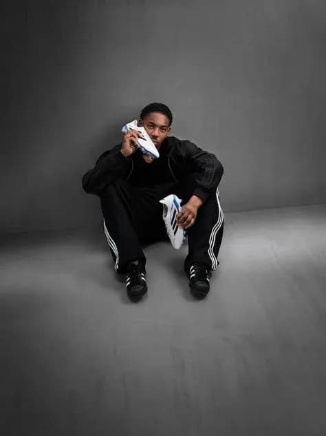 Athlete sitting on floor holding sports shoe Athlete sitting on floor holding sports shoe
