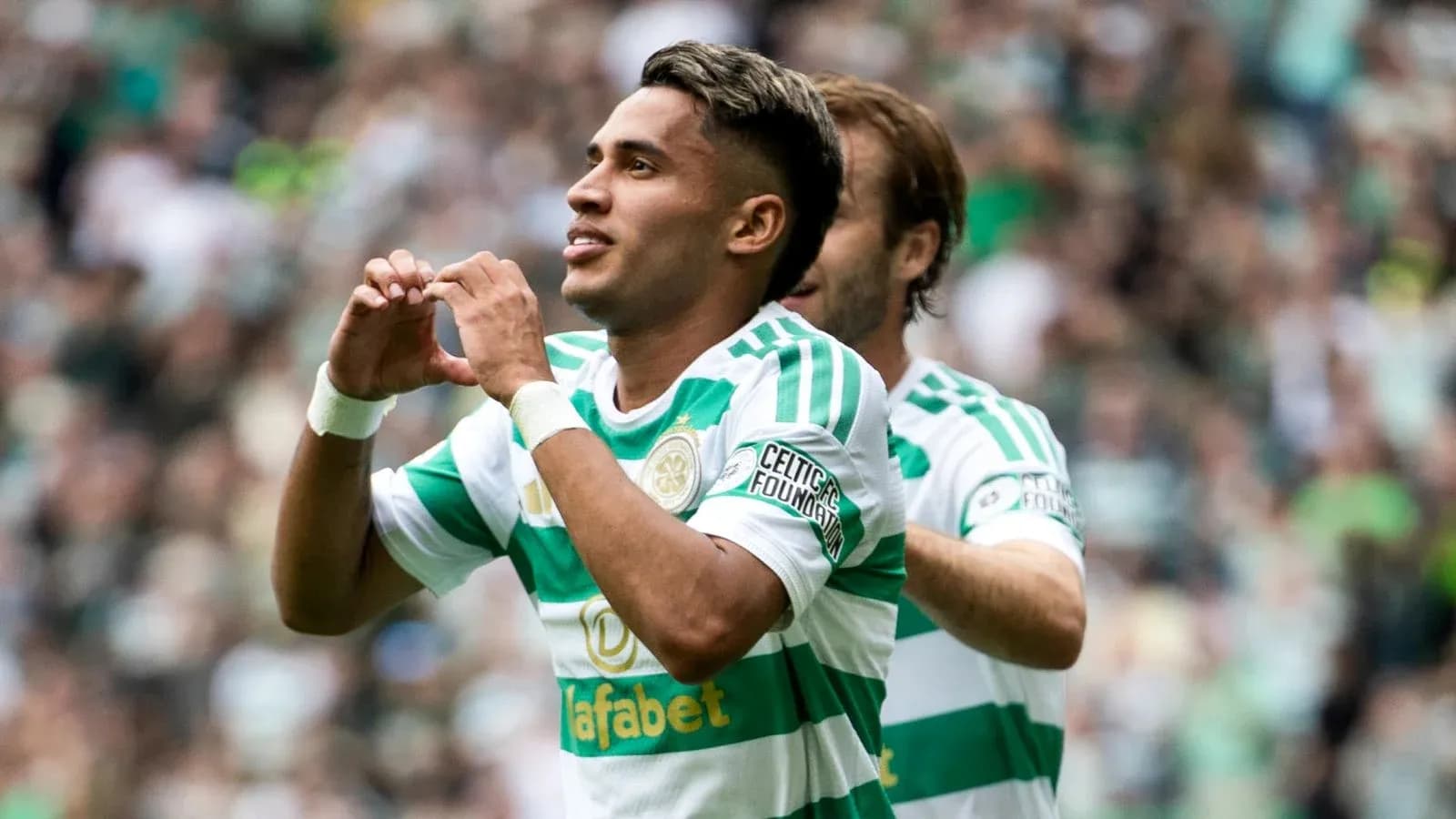Player celebrating goal with heart gesture on field Player celebrating goal with heart gesture on field