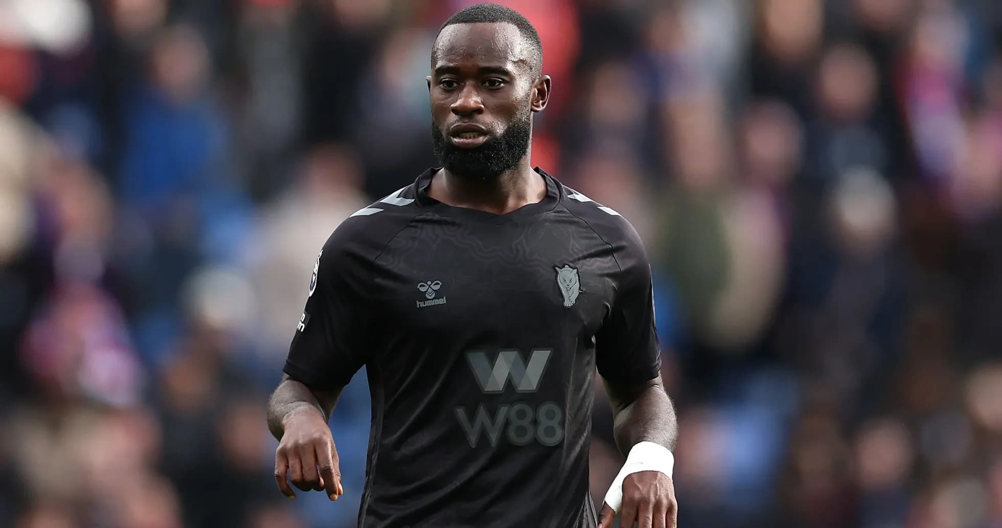 Player in black kit walking on the field Player in black kit walking on the field