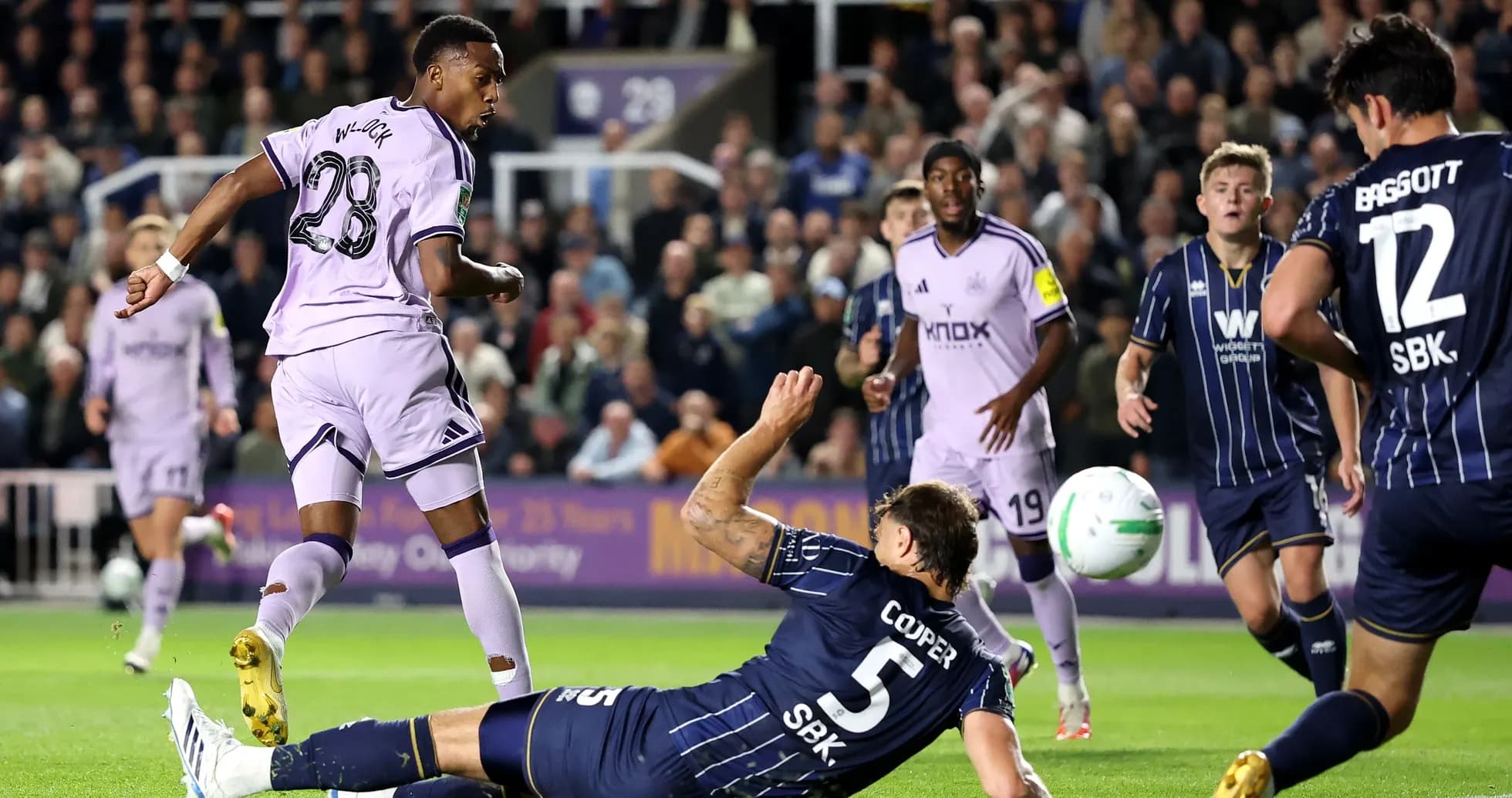 Player shooting on goal while defender falls Player shooting on goal while defender falls