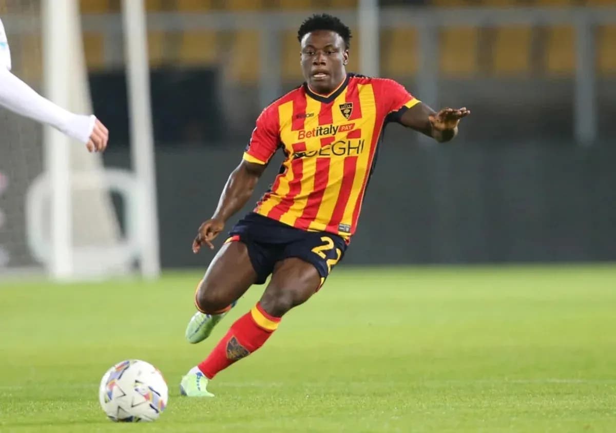 Player in red and yellow kit dribbling ball on field Player in red and yellow kit dribbling ball on field