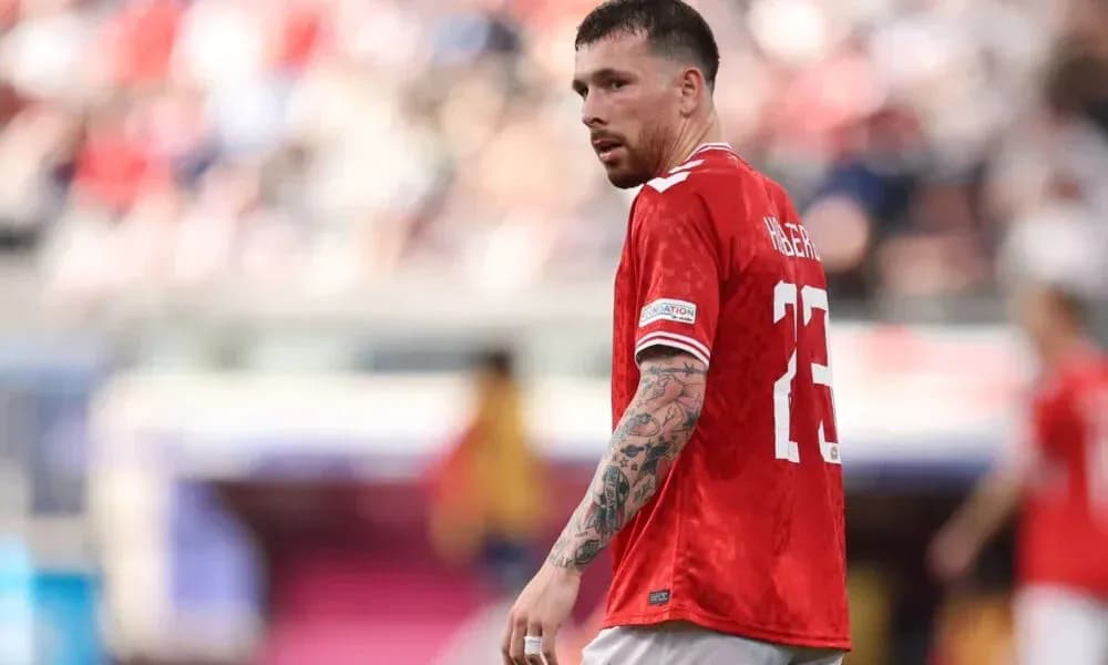 Player in red jersey on football pitch during match Player in red jersey on football pitch during match