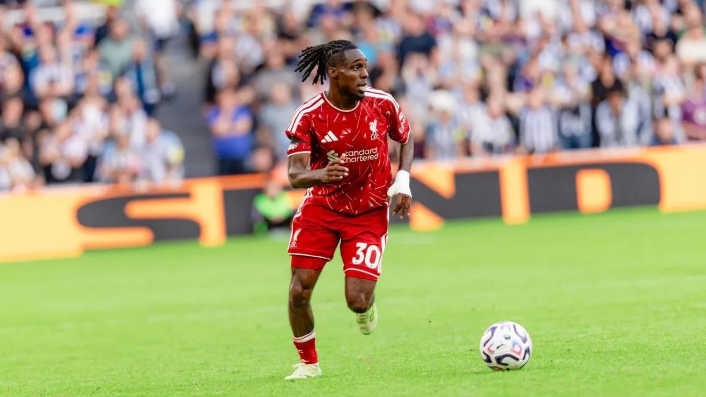 Player in red kit running with soccer ball on field Player in red kit running with soccer ball on field