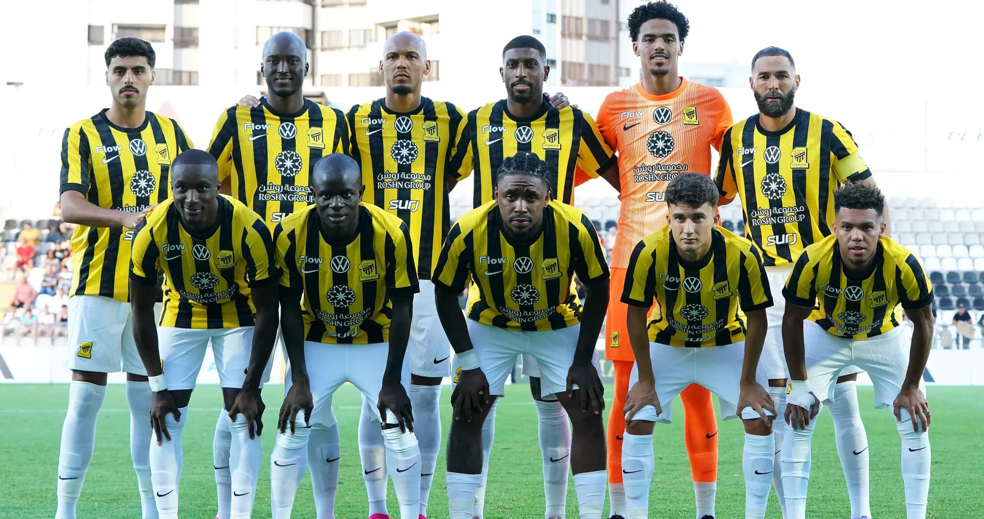 Football team in black and yellow kits posing for photo Football team in black and yellow kits posing for photo