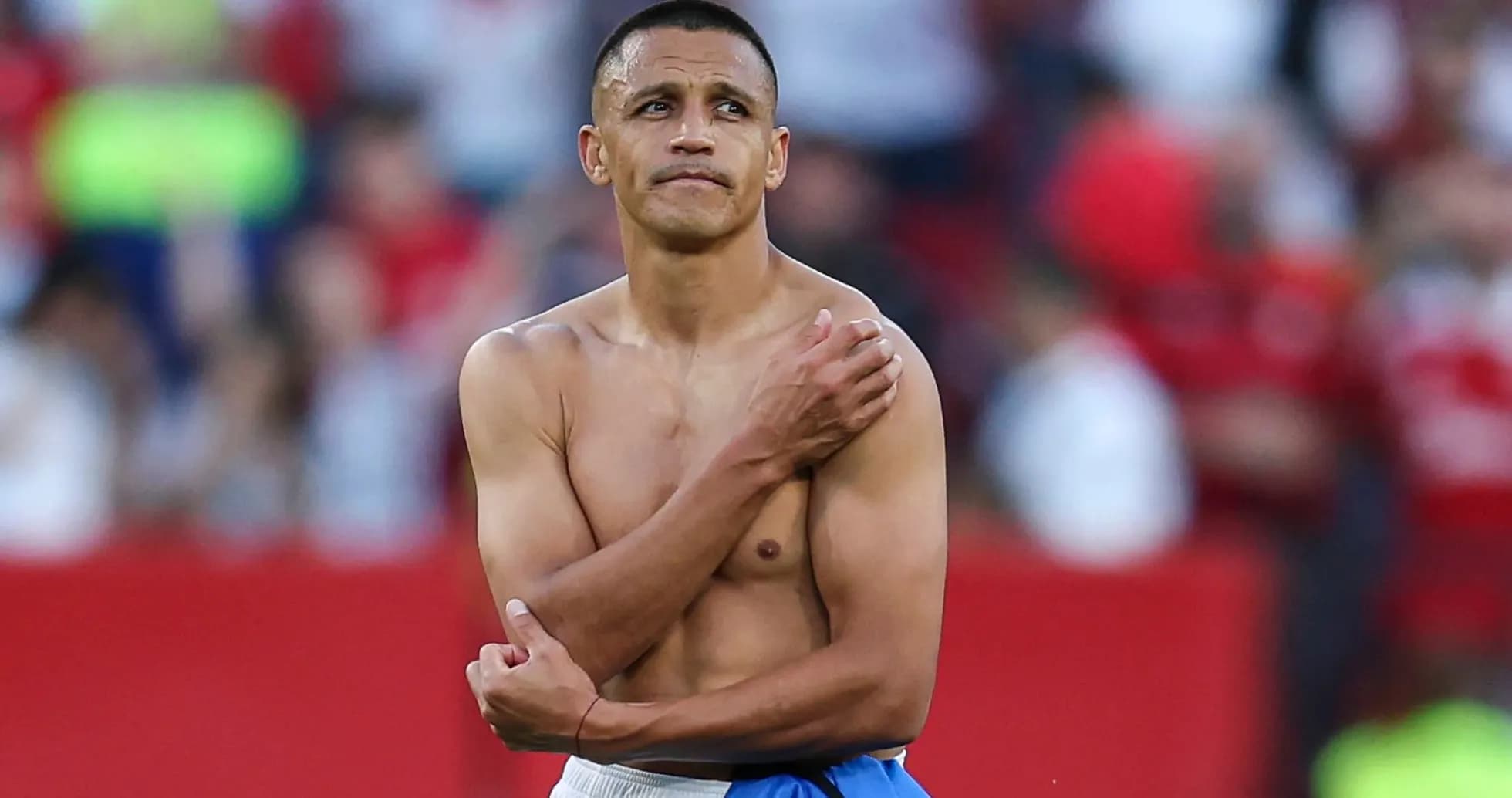 Player with shirt off on the pitch post-match Player with shirt off on the pitch post-match